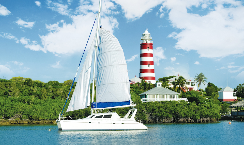 Sailboat yacht in font of lighthouse in Hope Town Abaco in The Bahamas